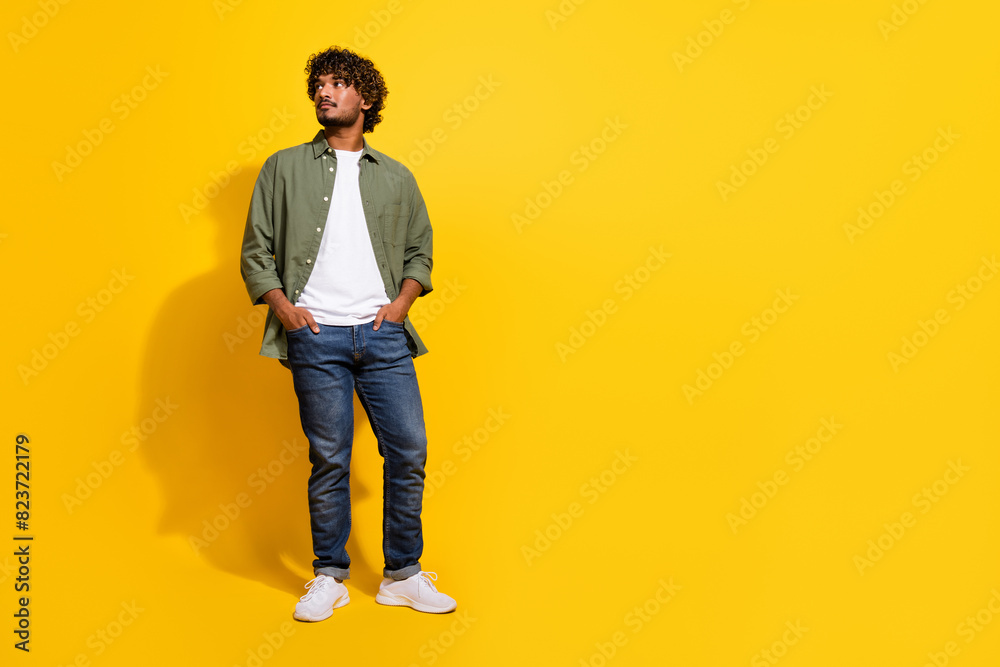 Fototapeta premium Portrait photo of young handsome model hispanic businessman look novelty in khaki shirt and jeans posing isolated on yellow color background