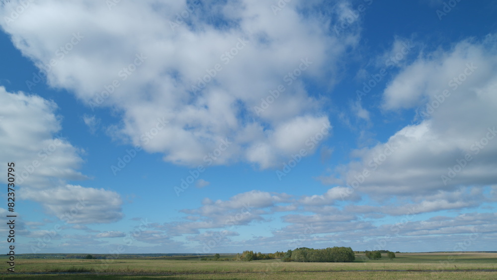 Mystic white clouds flying over green autumn field. Clouds fly across the blue sky. Timelapse.