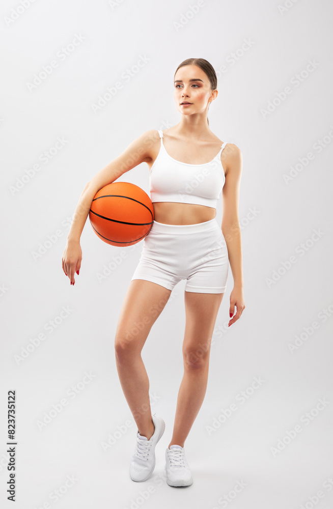 A beautiful slender girl athlete in white shorts and in top plays basketball. A beautiful slender girl athlete in white shorts and in top plays basketball.