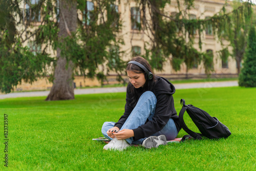 An upset girl student sits near the college with her head down.