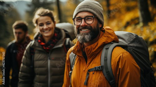 Happy couple in outdoor gear enjoying a hike among beautiful autumn trees and foliage with friends