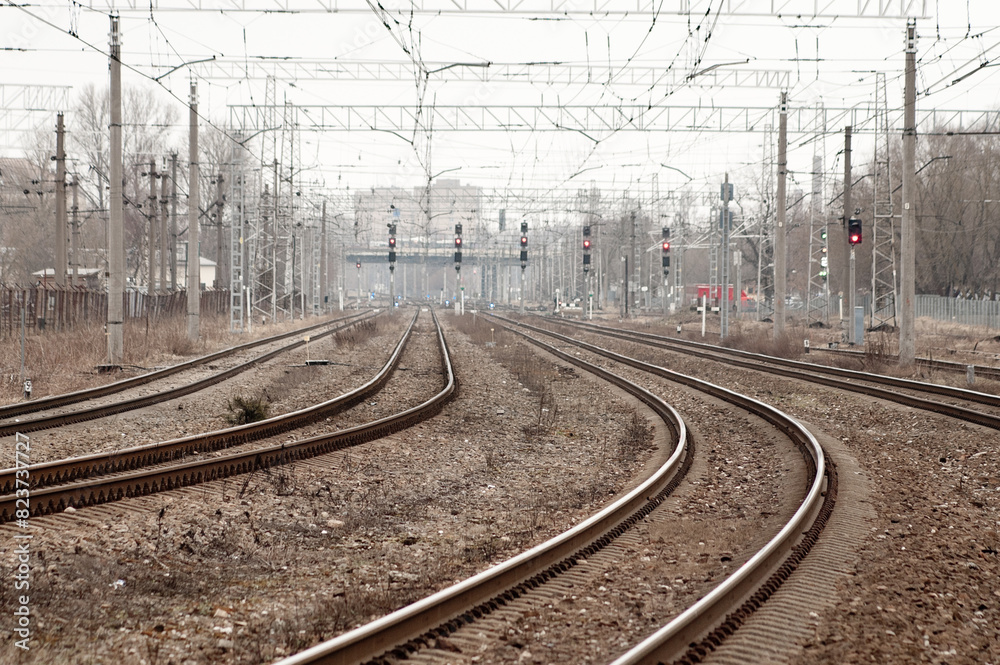 railroad tracks and traffic lights against a gray sky