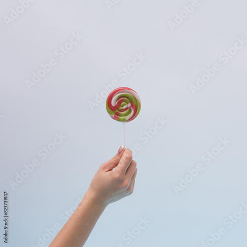 A woman's hand holds a New Year's lollipop..Minimal composition, creative art.