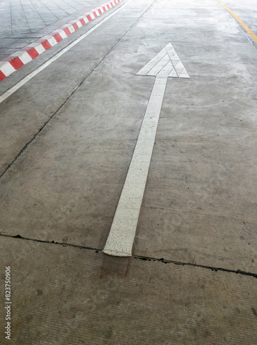 The white arrow sign on the concrete street.