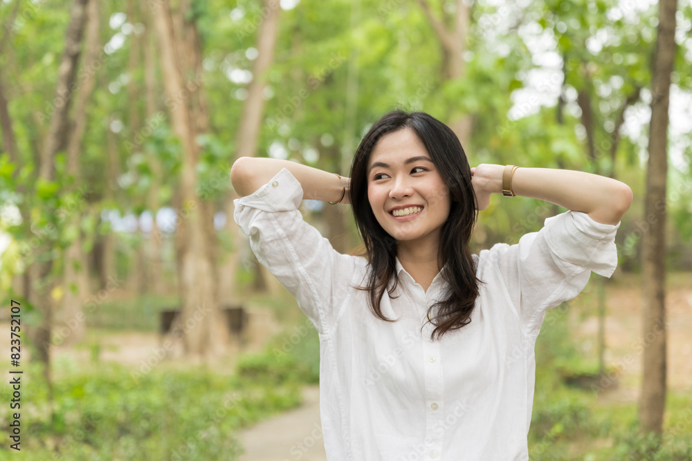 Portrait of asian woman breathing fresh air in a forest.Carefree asian girl smiling and enjoying summer sunny day in park.Young woman arms raised enjoying the fresh air in green park. Portrait of asian woman breathing fresh air in a forest.Carefree asian girl smiling and enjoying summer sunny day in park.Young woman arms raised enjoying the fresh air in green park.