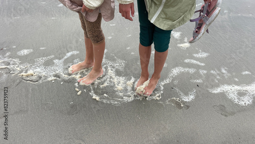 Kids' feet on the wet sand with sea foam photo