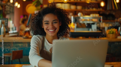 A beautiful mulatto young smiling woman working on a laptop   a freelance girl or a student at a computer in a cafe.
