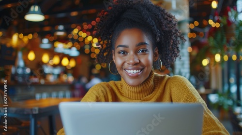 A beautiful mulatto young smiling woman working on a laptop, a freelance girl or a student at a computer in a cafe.