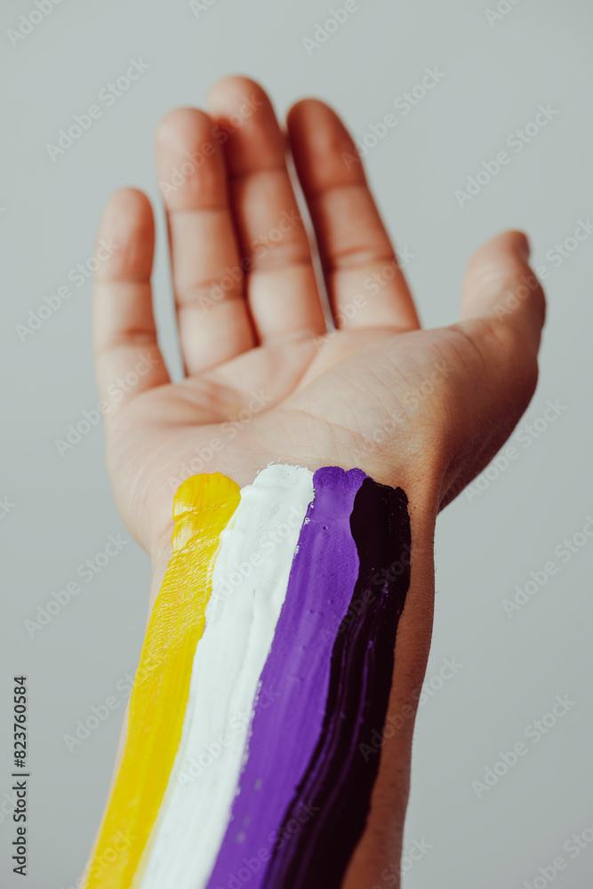 arm with the non-binary pride flag painted on it