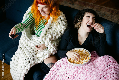 Two Friends Laughing on the Couch Watching TV Together