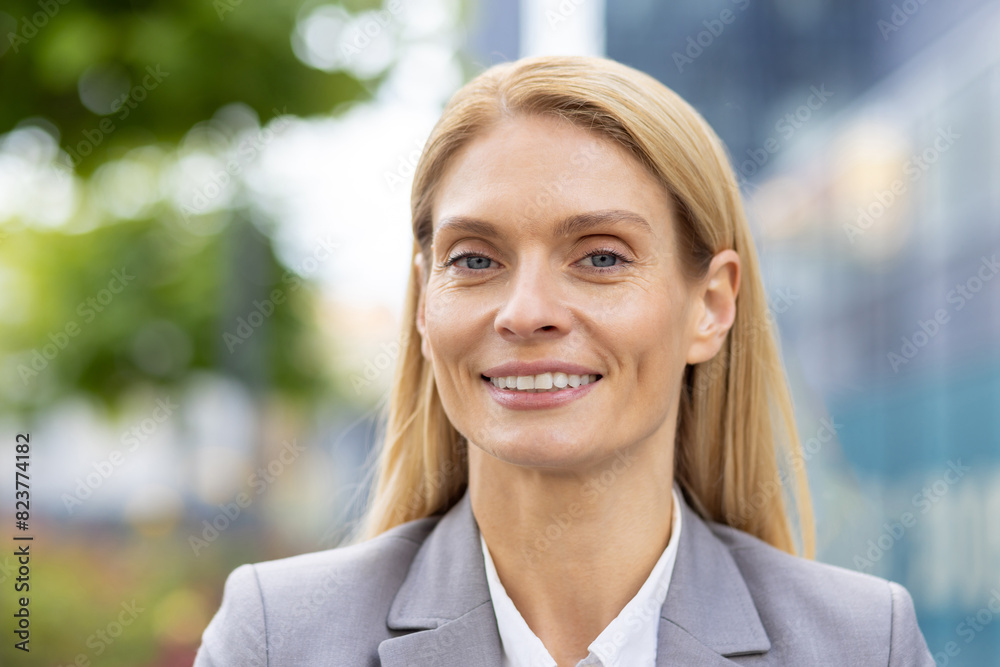 This image features a confident businesswoman smiling outdoors, capturing her natural light radiance and professional demeanor. The background shows a modern, blurry urban setting. This image features a confident businesswoman smiling outdoors, capturing her natural light radiance and professional demeanor. The background shows a modern, blurry urban setting.