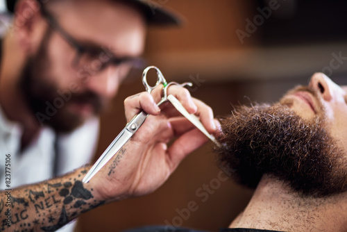 Beard, client and man in barbershop with scissors, cut and tools for trendy facial hair care at small business. Style, barber and customer in chair for grooming service, haircut skills and clean trim