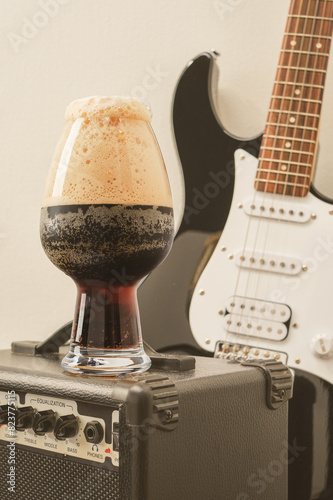 Beer and guitar. Tube combo or amplifier for guitar with electric guitar and glass of stout beer. Selective focus. Toned image.