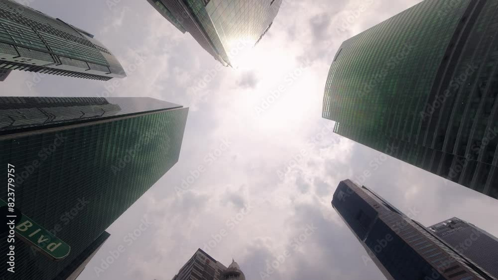 Zoom in marina boulevard sign and POV camera straight up through modern skyscraper buildings with blue sky. POV view of city skyline buildings. Modern business district