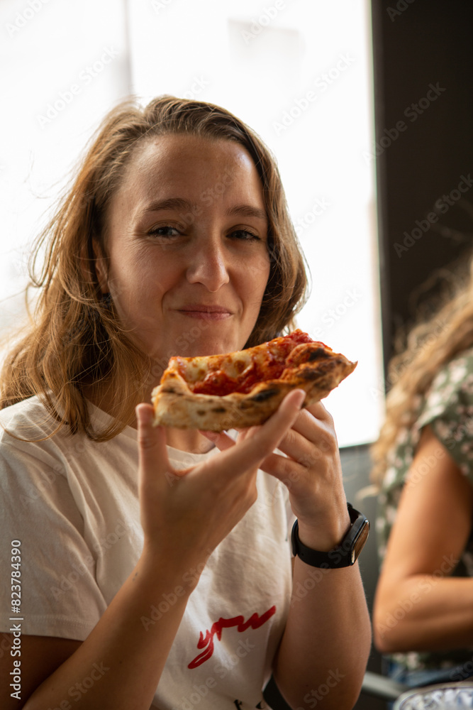 Young woman smiles as she eats pizza Young woman smiles as she eats pizza
