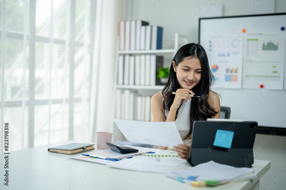 A woman is sitting at a desk with a computer and a tablet A woman is sitting at a desk with a computer and a tablet