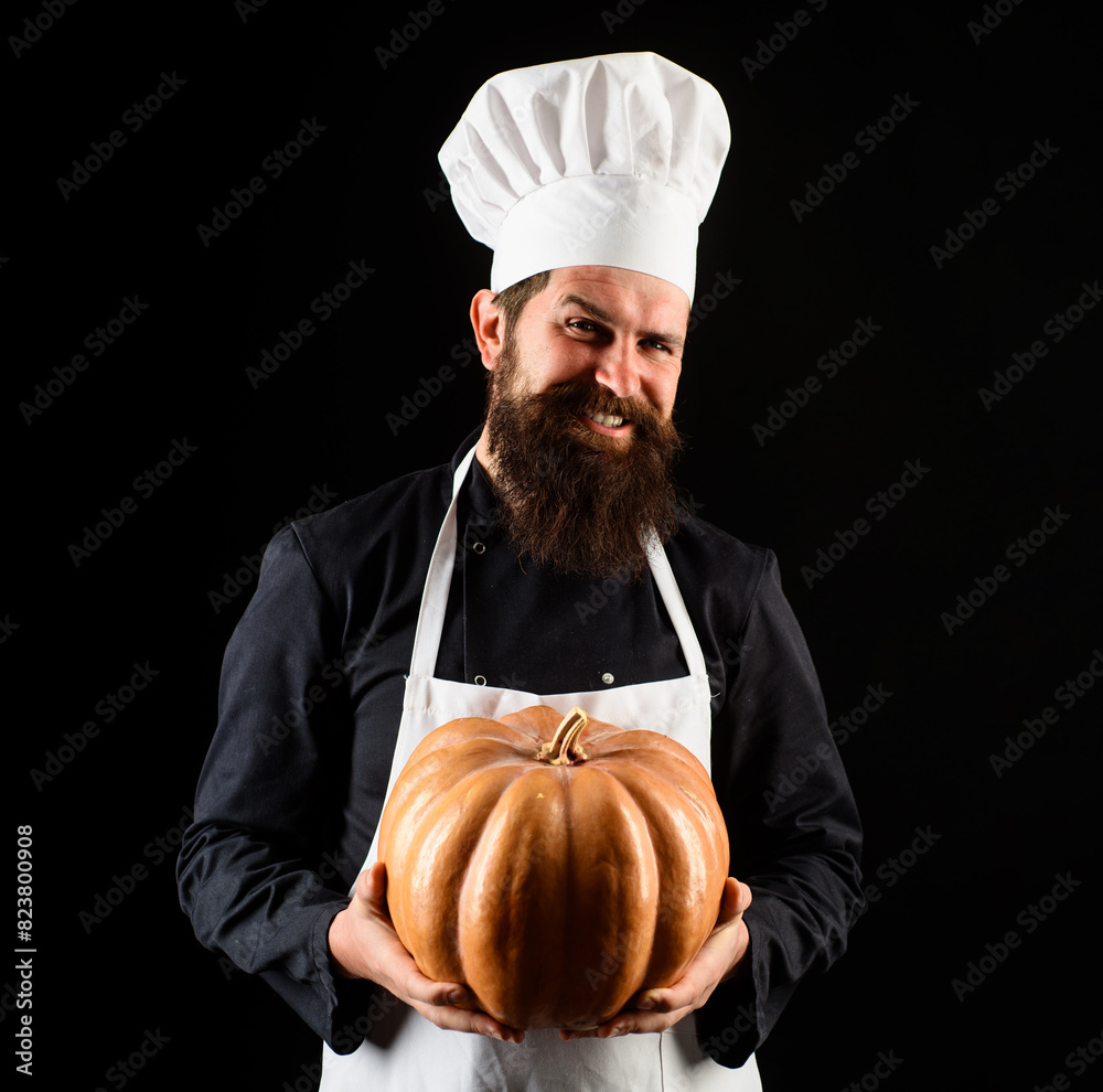 Smiling male chef in uniform with pumpkin. Bearded man in chef hat with squash. Organic food. Cook chef in white apron with pumpkin for culinary. Thanksgiving day. Autumn recipes. Seasonal vitamins.