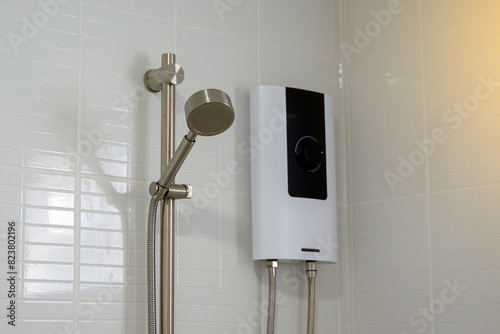Water heater shower in black and white tones and a metal hand shower set mounted on a white bathroom wall.