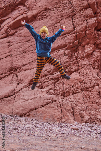 latin boy jumping in the air between a rock formation on a tour in Jujuy, Argentina