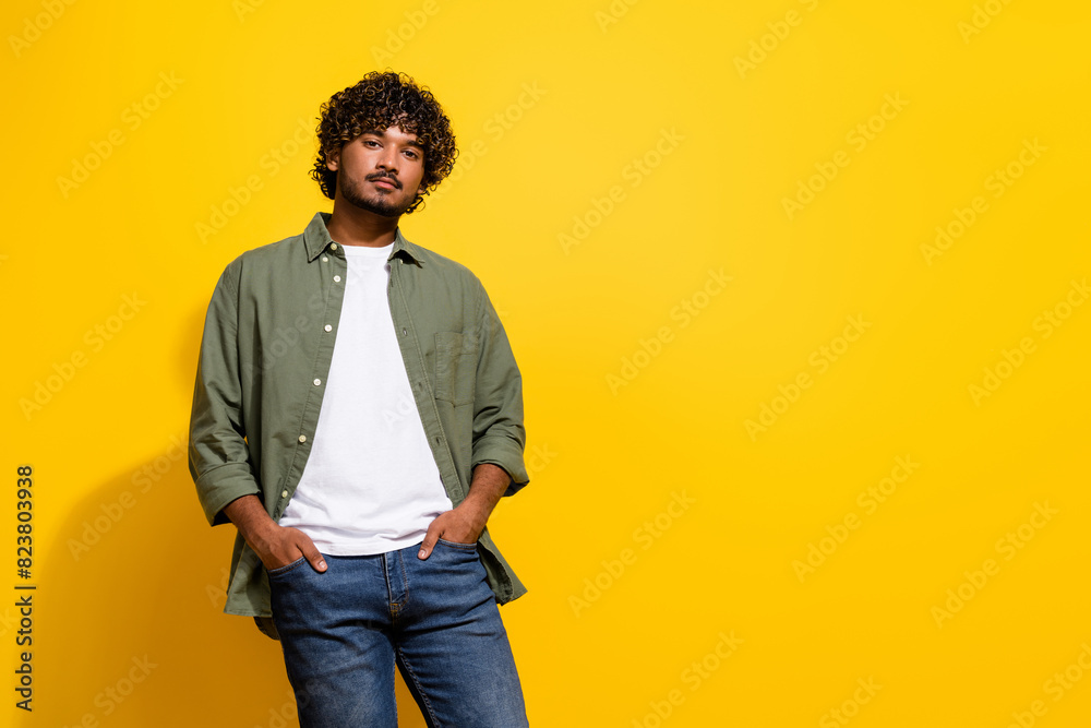 Photo of young handsome model hispanic guy empty space in khaki shirt and jeans posing exclusive brand isolated on yellow color background Photo of young handsome model hispanic guy empty space in khaki shirt and jeans posing exclusive brand isolated on yellow color background