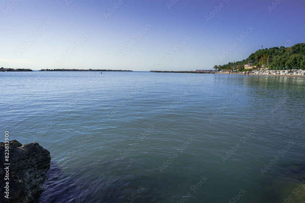 Calm watery seascape with textured rocks in the foreground reflecting the clear sky above, representing relaxation and beauty of nature, oneness with nature Calm watery seascape with textured rocks in the foreground reflecting the clear sky above, representing relaxation and beauty of nature, oneness with nature