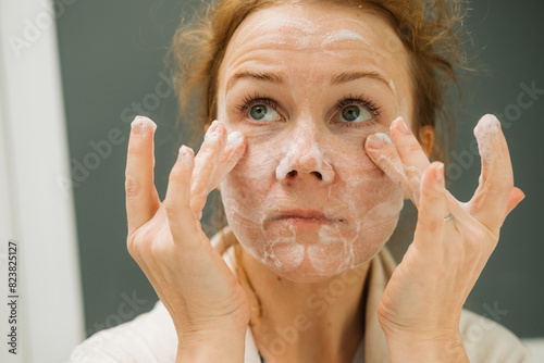 Close up of a woman applying foam on her face photo