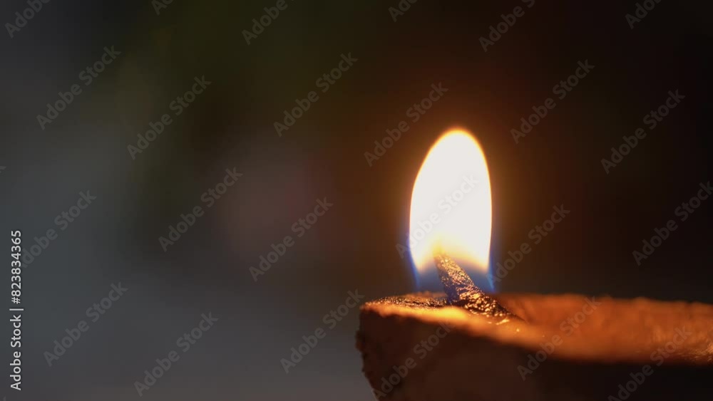 macro close up shot of flame from an oil covered cotton wick in an organic plant fiber diya clay lamp showing the celebrations on the festival of diwali in India