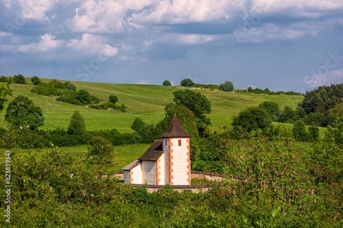 Beautiful green meadows with trees and a historic building. Early Gothic church of St. Matthew in the village of Zolna, near Zvolen, central Slovakia. © Ivan