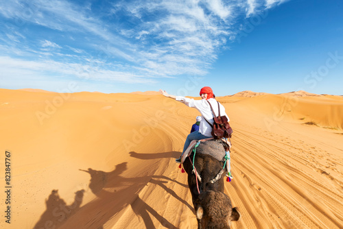 Girl riding a camel in the Sahara desert in Morocco. Camel expedition in the desert.