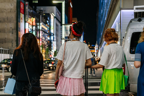 Young women waiting to cross a zebra crossing along a shopping street photo