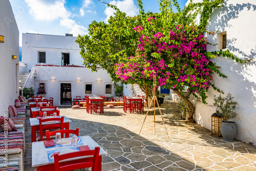 Typical Greek taverna restaurant with red chairs and bougainvillea flowers on square in Apollonia village, Sifnos island, Greece photo