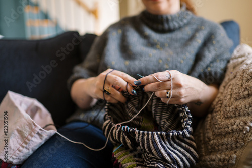 woman relaxing at home on sofa and knitting with two strands of yarn photo