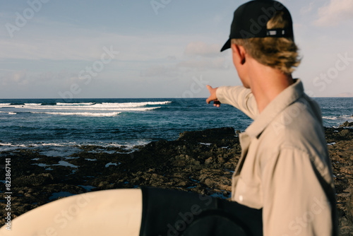 A man points towards the sea, signaling the perfect spot for surfing photo