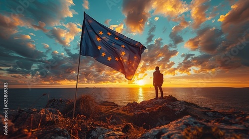 A striking image capturing a person silhouetted against a sunset sky, holding a fluttering European Union flag on a rugged coastline photo