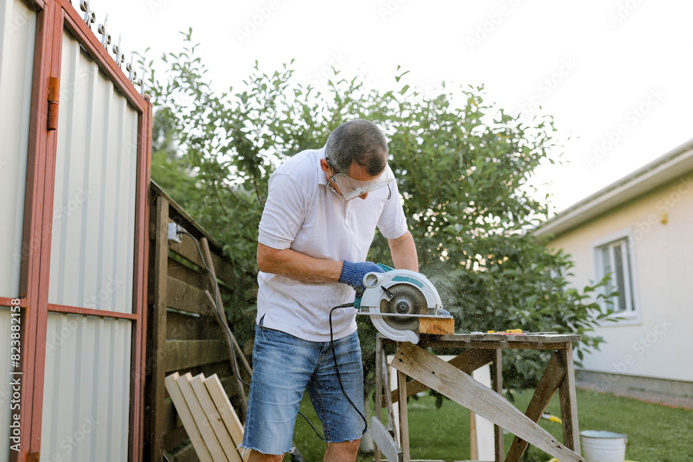 a man processes wood in the yard a man processes wood in the yard