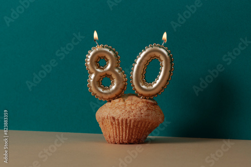 lit candles forming the number 80 on a muffin photo