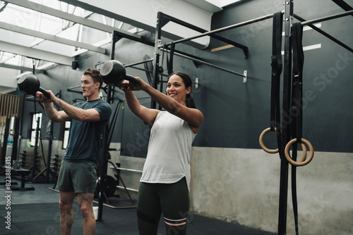 Positive athletes exercising with kettlebell in modern gym photo