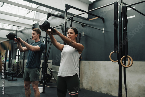 Strong sportspeople swinging kettlebell while working out in gym photo