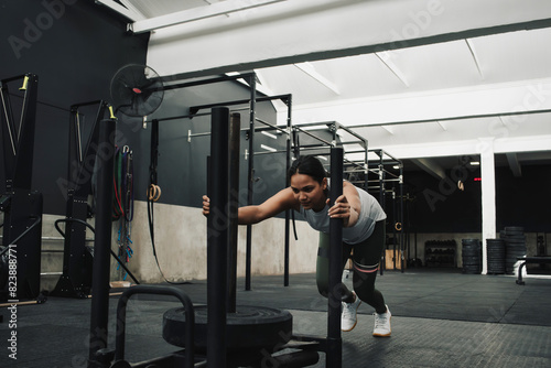 Athletic female pushing uprise bars while doing exercises in gym photo