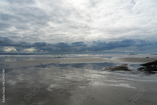 De beaux reflets des nuages sur le sable mouillé d'une plage de la presqu'île de Crozon, sous un ciel parsemé de quelques nuages blancs à marée basse. photo