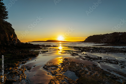Le soleil se couche sur une plage de la presqu'île de Crozon, en Bretagne, teintant le ciel de jaune et baignant le sable doré d'une lumière douce, tandis que l'océan murmure doucement. photo