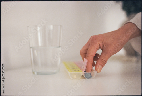 Woman taking pills and vitamins from pillbox photo