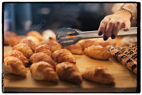 Baker picking croissant with tongs photo