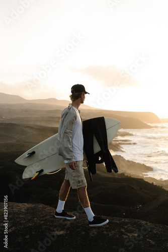 A youthful surfer explores the shores searching for the perfect waves photo