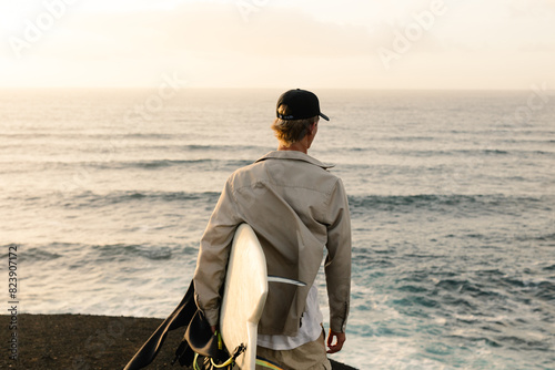 A young surfer marvels at the waves crashing against the shore photo