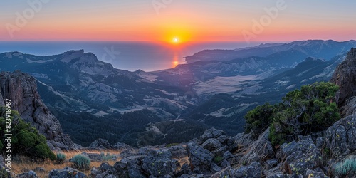 Stunning panoramic view of a vibrant sunset overlooking a scenic mountain range and valley leading to the calm ocean, capturing nature's grandeur and tranquil beauty © aicandy