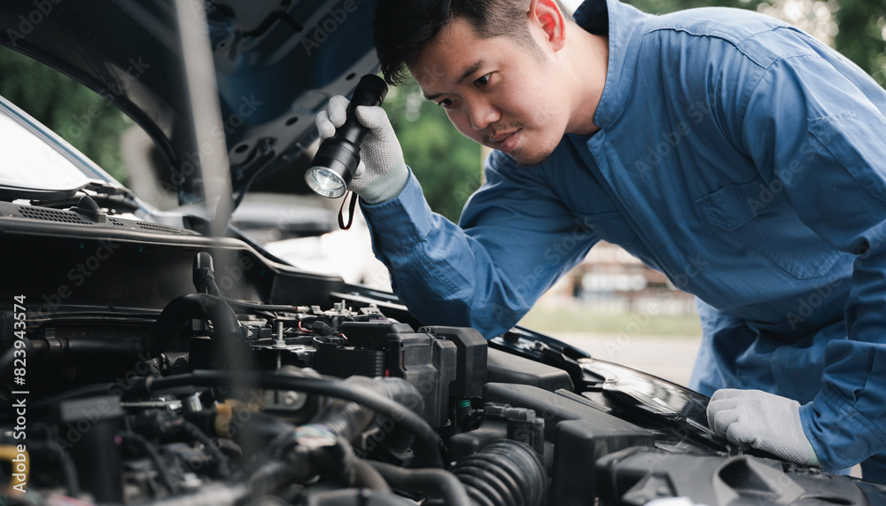 © sorapop - Car mechanic repairer analyzing car problems with an electric lamp while working on the cradle. Side view of expert technician repairing a car in the workshop. © sorapop - Car mechanic repairer analyzing car problems with an electric lamp while working on the cradle. Side view of expert technician repairing a car in the workshop.