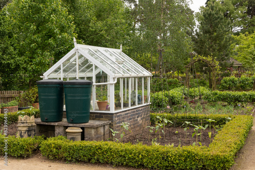Fototapeta premium white greenhouse in a small well maintained vegetable garden, growing fresh organic food concept