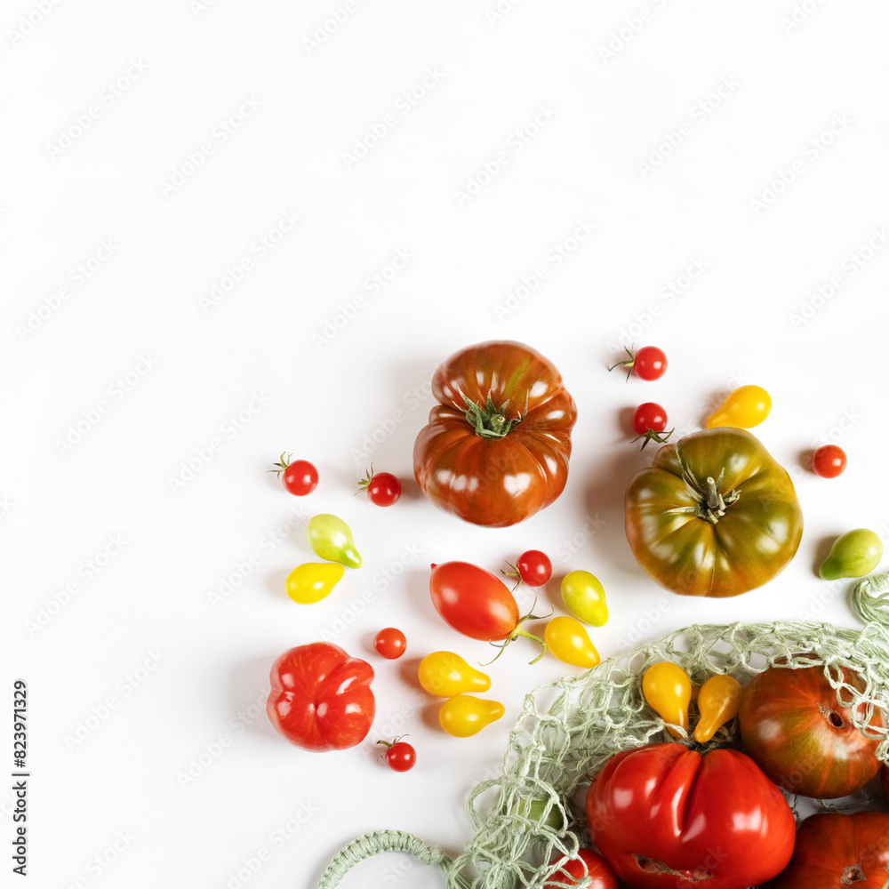 Red, green, yellow and striped tomatoes in string bag on gray table with space for text. Healthy food, fresh healthy vegetables from the garden Red, green, yellow and striped tomatoes in string bag on gray table with space for text. Healthy food, fresh healthy vegetables from the garden
