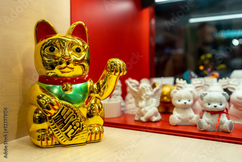 Maneki Neko, Japanese Lucky Cat in a gift shop window. Golden cat brings good luck and wealth closeup